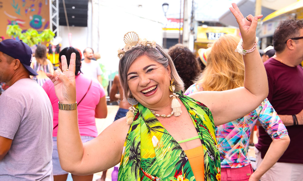 senhora sorrindo e com braços para cima posando para a foto